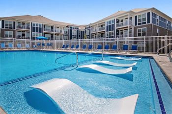 A large swimming pool with a white diving board and blue water.